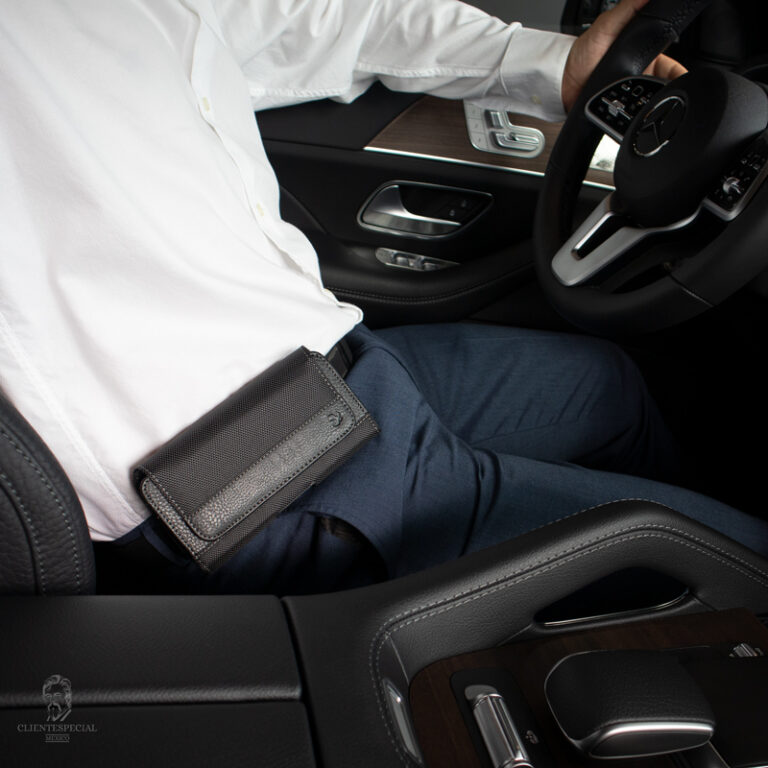 un caballero sentado frente al volante del auto y lleva enganchada en el pantalon una funda Cinturon de tela con clip para celular